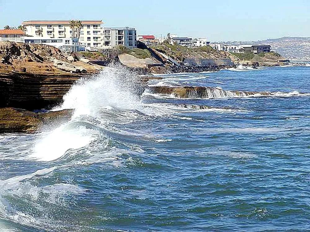 Onde bianche e azzurre si infrangono sulla costa.